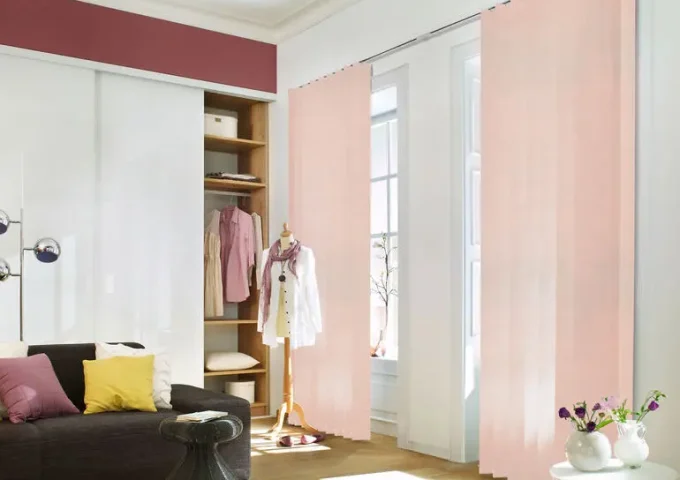 Innenraum mit rosa Lamellen vor Fenstern, montiert an einer Wand mit weisser Schiene