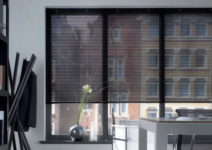 Schwarze Lamellen vor grossen Fenstern in einem hellen und modernen Büro oder Wohnraum