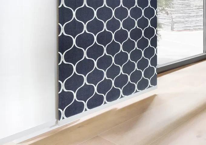 Dunkelblaue Stoffbahn mit weissem geometrischem Muster vor einem Fenster und hellem Holzfussboden