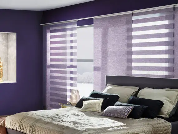 Flächenvorhänge in Lila an einer Wand montiert über einem grossen Fenster im Schlafzimmer