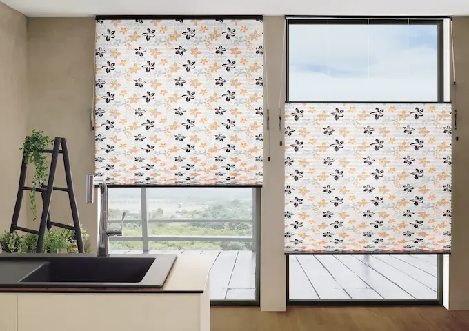 Zwei grosse Fenster mit halbtransparentem Faltstoff in Weiss mit Blumenmuster als Sichtschutz in einer Küche
